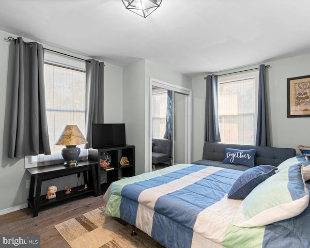 bedroom with a closet, multiple windows, and dark hardwood / wood-style floors