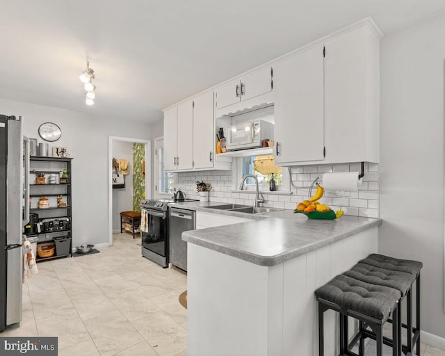 kitchen with stainless steel appliances, sink, plenty of natural light, white cabinets, and tasteful backsplash