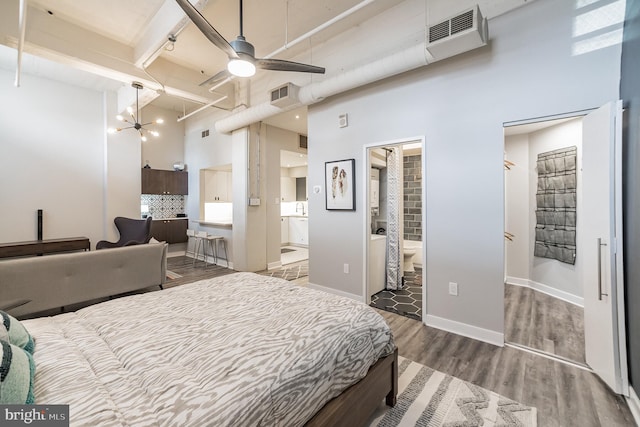 bedroom with a high ceiling, beamed ceiling, ceiling fan, hardwood / wood-style floors, and connected bathroom