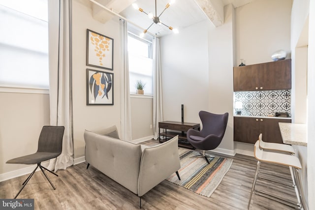 sitting room featuring a notable chandelier, beam ceiling, and hardwood / wood-style floors