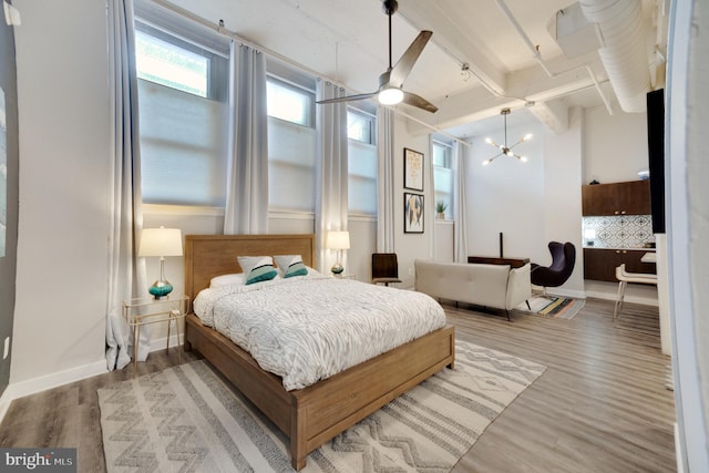 bedroom with ceiling fan with notable chandelier, beam ceiling, and hardwood / wood-style floors