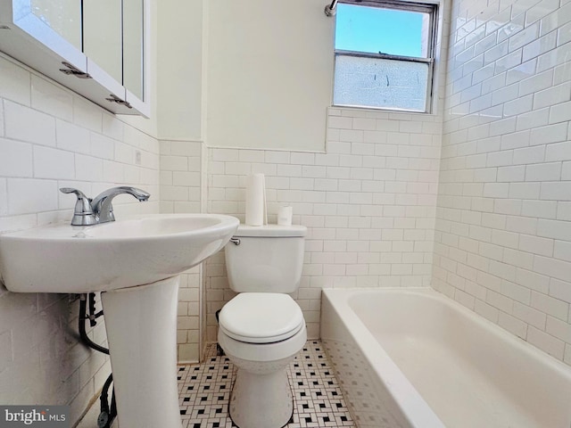 bathroom with tile walls, a tub to relax in, and toilet