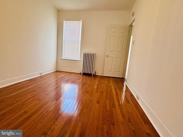 unfurnished room featuring radiator heating unit and dark hardwood / wood-style flooring