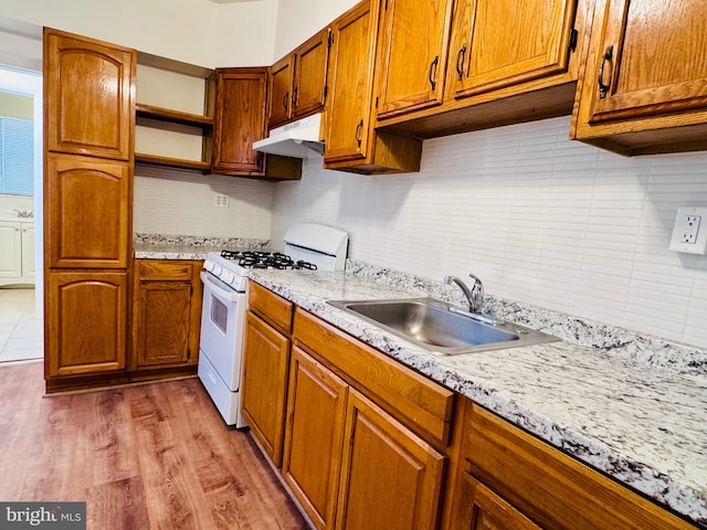 kitchen with decorative backsplash, sink, light wood-type flooring, and gas range gas stove