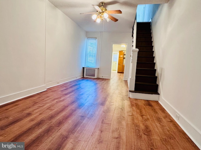 unfurnished living room featuring hardwood / wood-style flooring, ceiling fan, and radiator