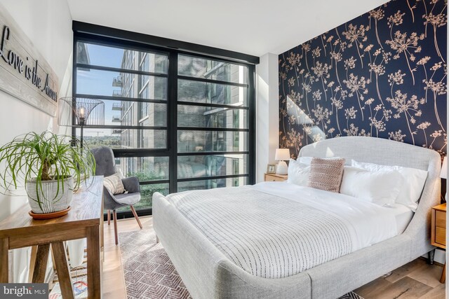 bedroom with floor to ceiling windows and hardwood / wood-style floors