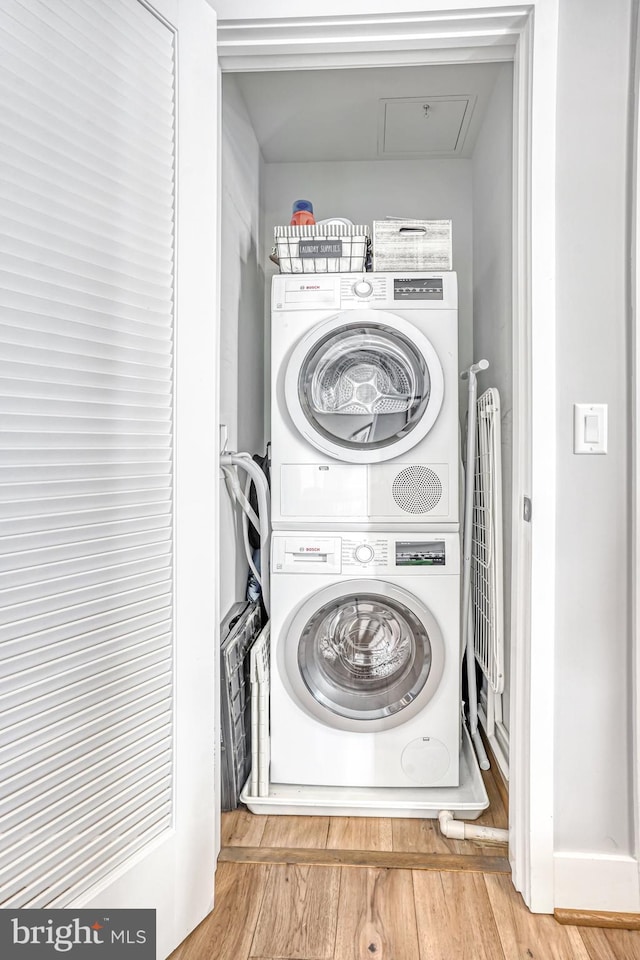 laundry area featuring wood-type flooring and stacked washer / drying machine