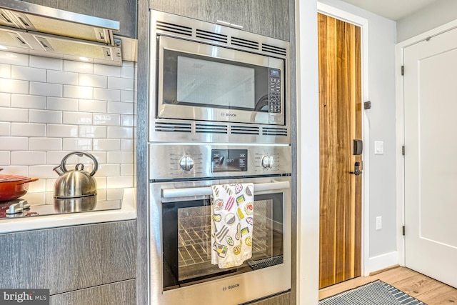 kitchen with stainless steel appliances, light hardwood / wood-style floors, and backsplash