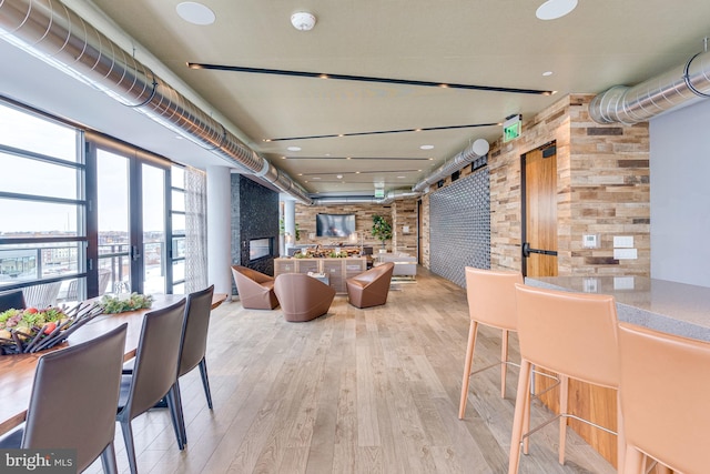 dining area with brick wall, light wood-type flooring, and french doors