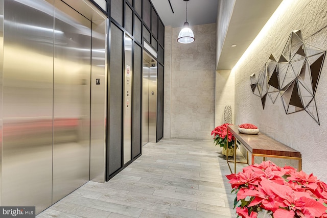 hall featuring tile walls, elevator, and light hardwood / wood-style flooring