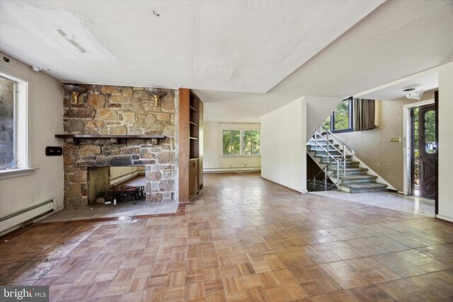 unfurnished living room featuring a stone fireplace, a textured ceiling, and parquet floors