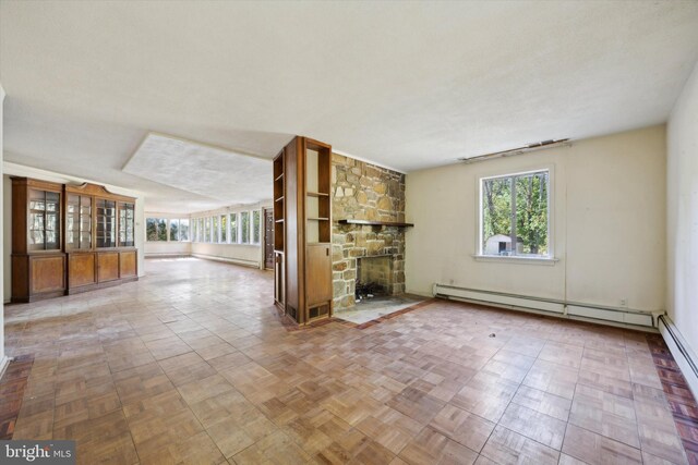 unfurnished living room featuring baseboard heating, a fireplace, and parquet floors