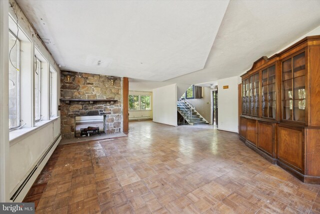 unfurnished living room with baseboard heating and a fireplace