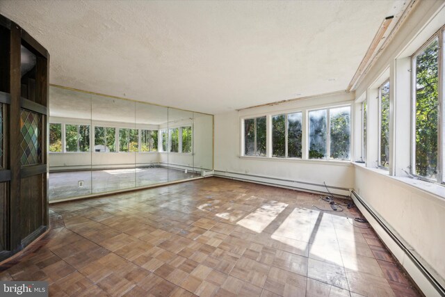 unfurnished sunroom with plenty of natural light and a baseboard radiator