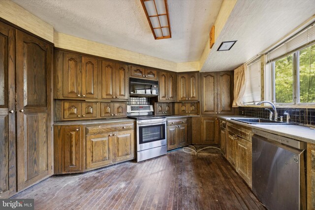 kitchen featuring sink, appliances with stainless steel finishes, dark hardwood / wood-style floors, and a textured ceiling