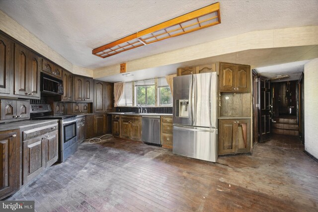 kitchen with dark hardwood / wood-style flooring, a textured ceiling, sink, dark brown cabinetry, and stainless steel appliances