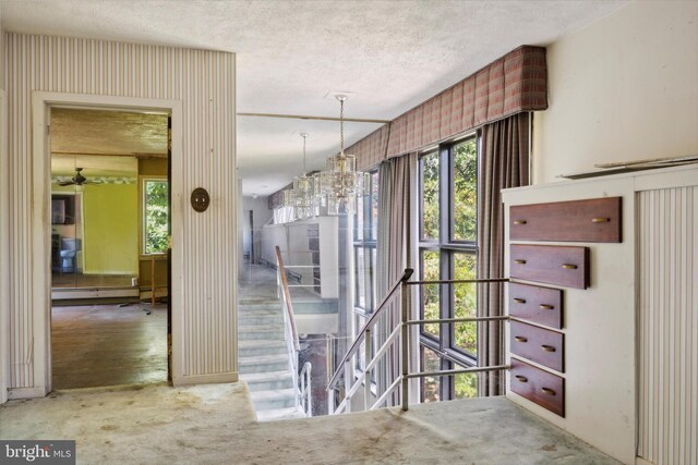 interior space with a textured ceiling, a baseboard radiator, a chandelier, and carpet