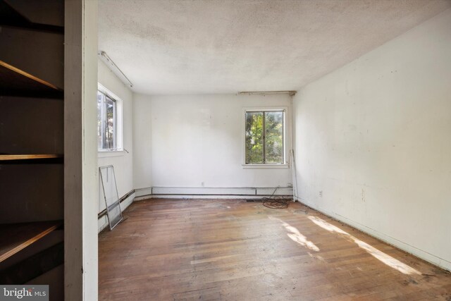 empty room with a textured ceiling and hardwood / wood-style flooring