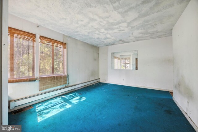 carpeted spare room with a baseboard radiator