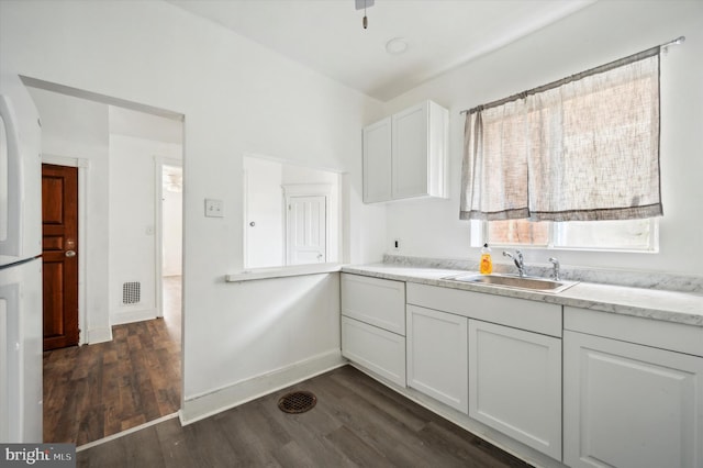 kitchen featuring dark wood-type flooring, sink, and white cabinets