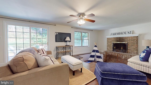 living room featuring a brick fireplace, hardwood / wood-style floors, and ceiling fan