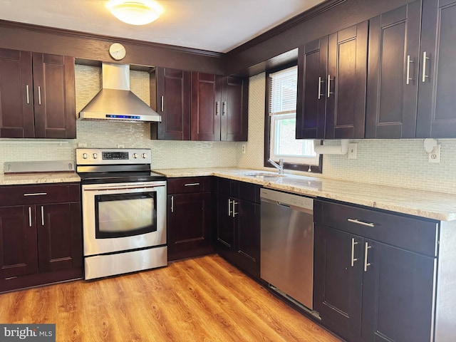 kitchen with crown molding, light stone counters, wall chimney exhaust hood, stainless steel appliances, and tasteful backsplash