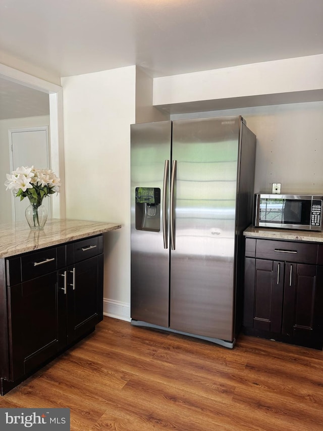 kitchen featuring appliances with stainless steel finishes, light stone counters, baseboards, and wood finished floors