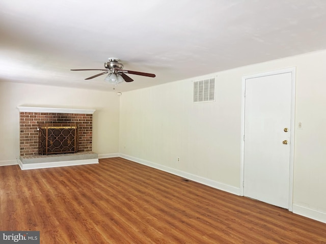 unfurnished living room with ceiling fan, visible vents, a fireplace, wood finished floors, and baseboards