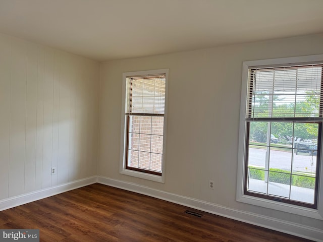 unfurnished room with visible vents, dark wood finished floors, and baseboards