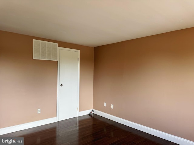 empty room with baseboards, dark wood finished floors, and visible vents