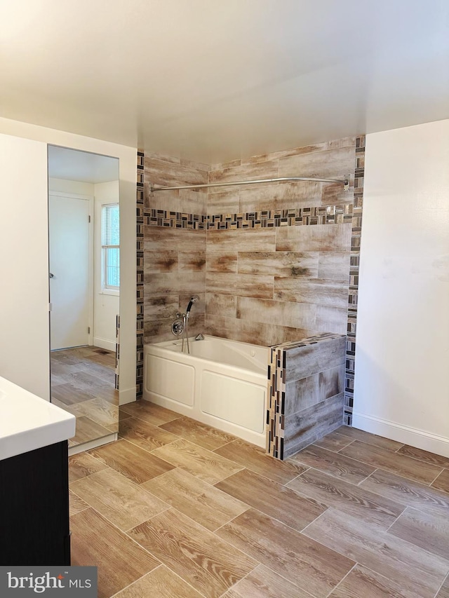 full bath featuring vanity, a bath, and wood finished floors