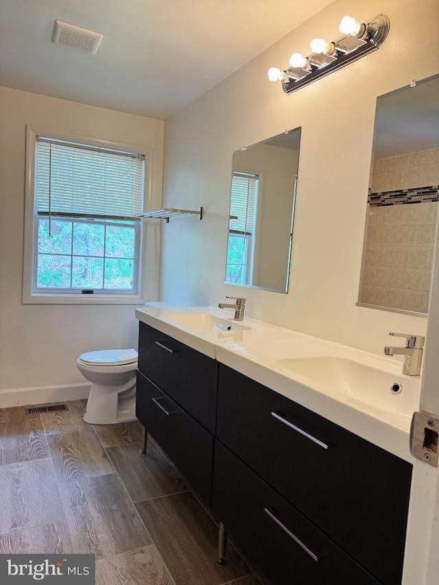 bathroom with double vanity, toilet, visible vents, and a sink