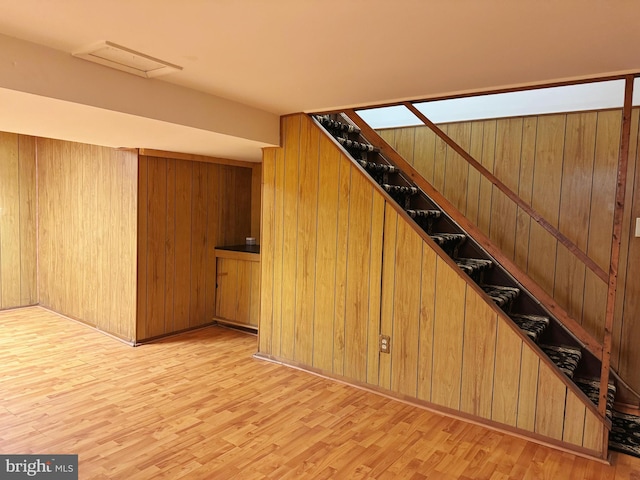 below grade area featuring light wood finished floors and wooden walls
