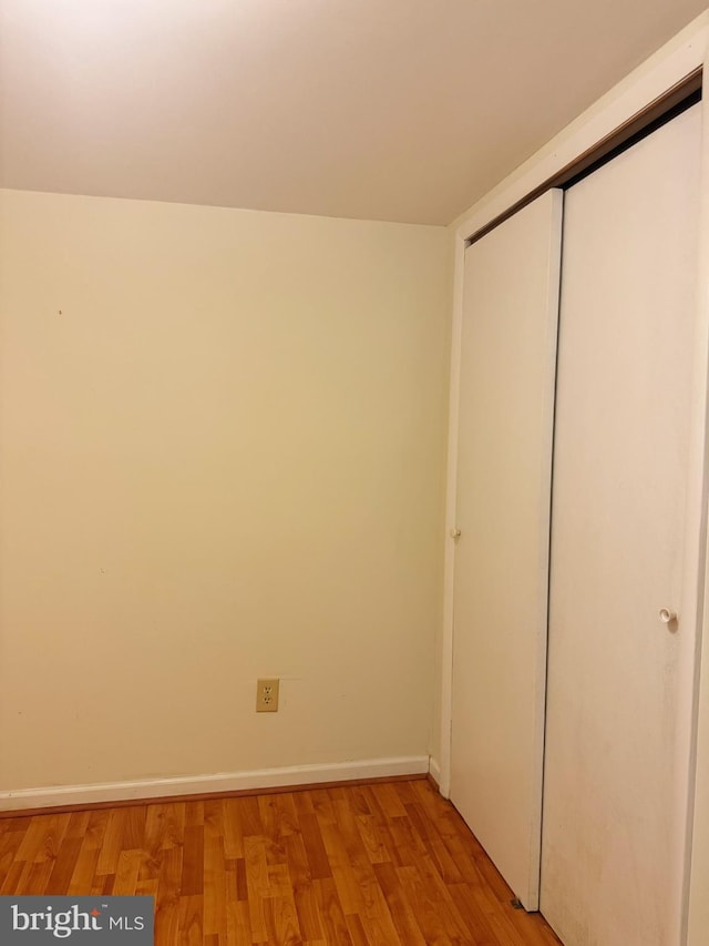 unfurnished bedroom with light wood-style floors, baseboards, and a closet