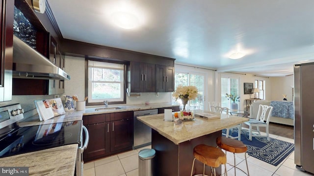 kitchen featuring stainless steel appliances, plenty of natural light, sink, and a center island