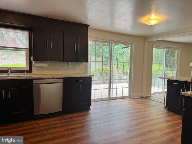 kitchen with light stone counters, a sink, dishwasher, tasteful backsplash, and dark wood-type flooring