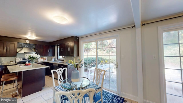 kitchen with stainless steel electric range, a kitchen island, wall chimney exhaust hood, a kitchen breakfast bar, and decorative backsplash