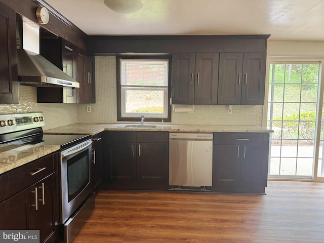 kitchen featuring wall chimney range hood, plenty of natural light, backsplash, and stainless steel appliances