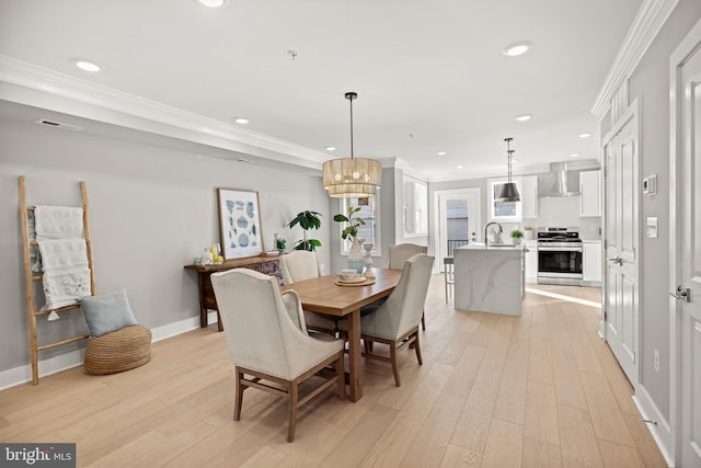 dining room with ornamental molding, light hardwood / wood-style flooring, and a chandelier