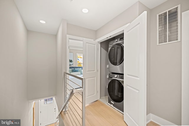 laundry area with light hardwood / wood-style flooring and stacked washer and clothes dryer