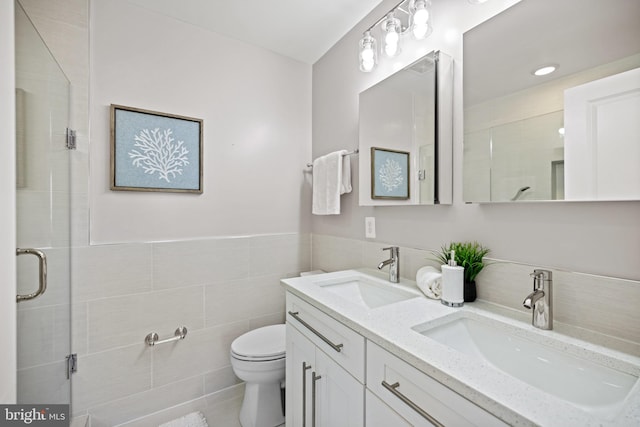 bathroom featuring vanity, toilet, tile walls, and a shower with shower door