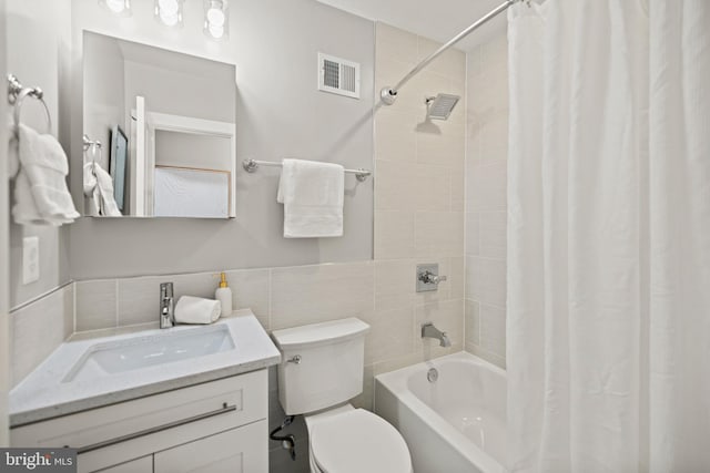 full bathroom with toilet, shower / tub combo with curtain, vanity, and tile walls