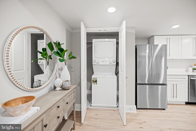 laundry room featuring stacked washer and clothes dryer and light wood-type flooring