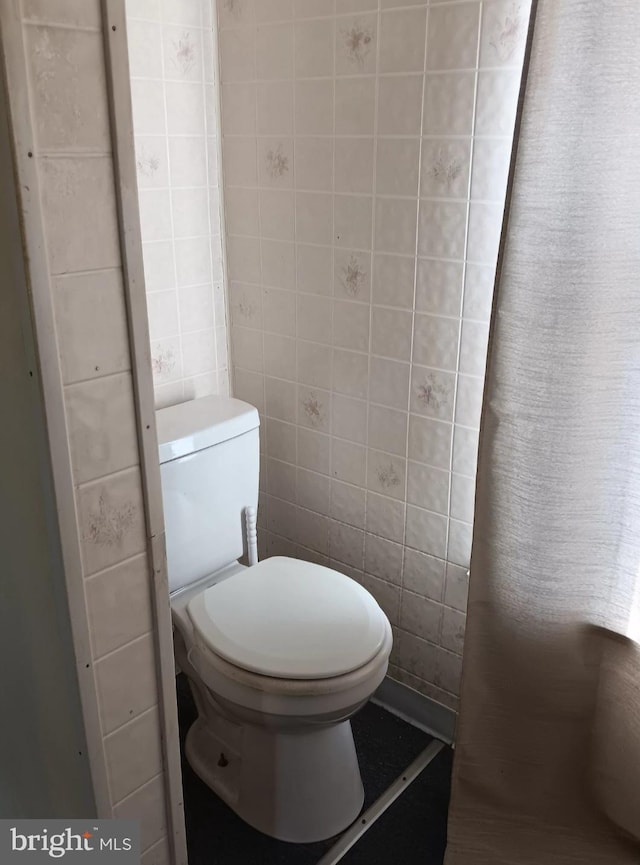 bathroom with toilet and tile walls