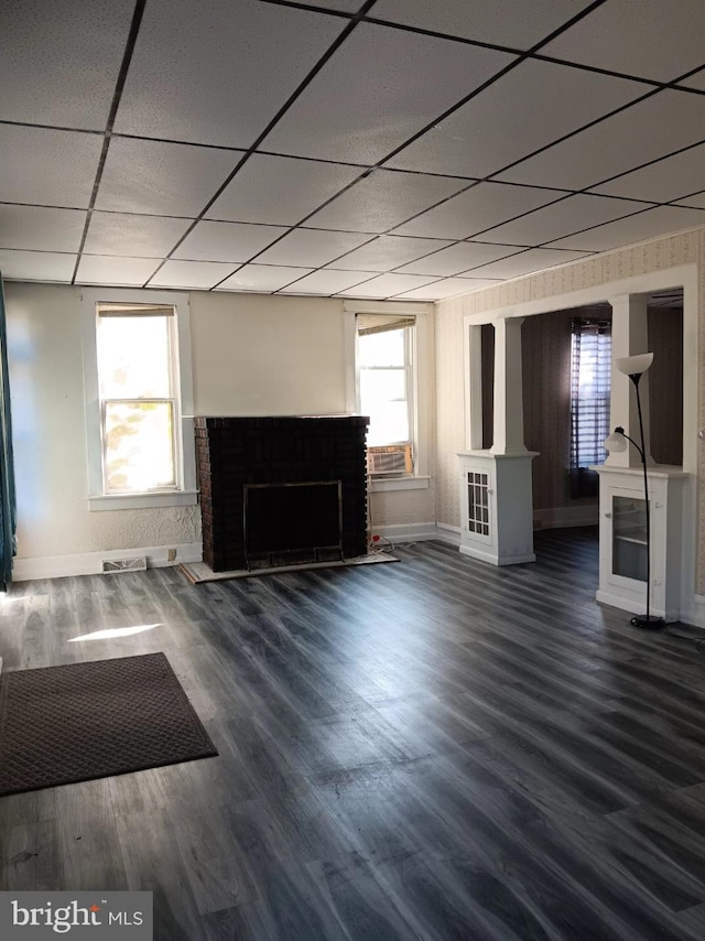 unfurnished living room with a paneled ceiling, dark wood-type flooring, and plenty of natural light