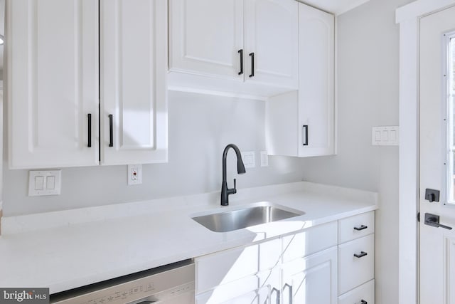 kitchen with dishwashing machine, white cabinetry, and sink