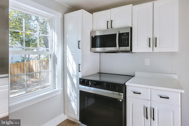 kitchen featuring white cabinets, stainless steel appliances, hardwood / wood-style floors, and a healthy amount of sunlight