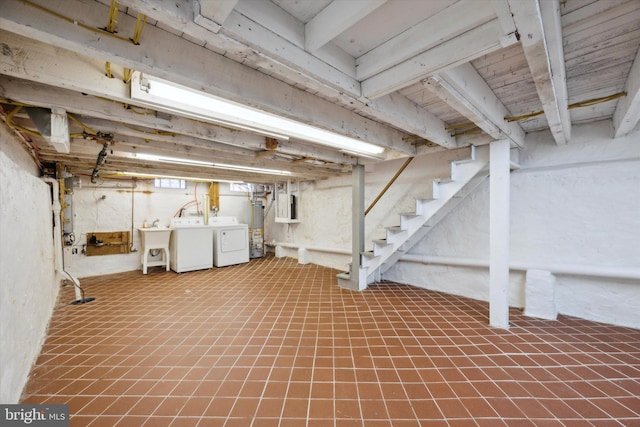 basement with water heater, electric panel, sink, and washing machine and dryer