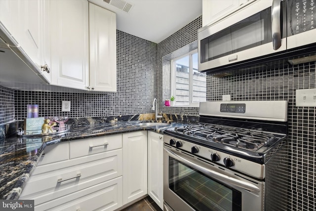 kitchen featuring dark stone counters, decorative backsplash, white cabinetry, and stainless steel appliances