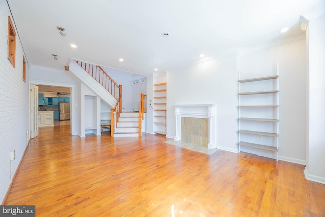 unfurnished living room featuring ornamental molding and light hardwood / wood-style flooring